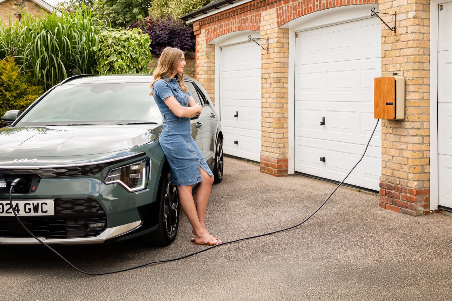 A home EV charger beside a car on a residential driveway