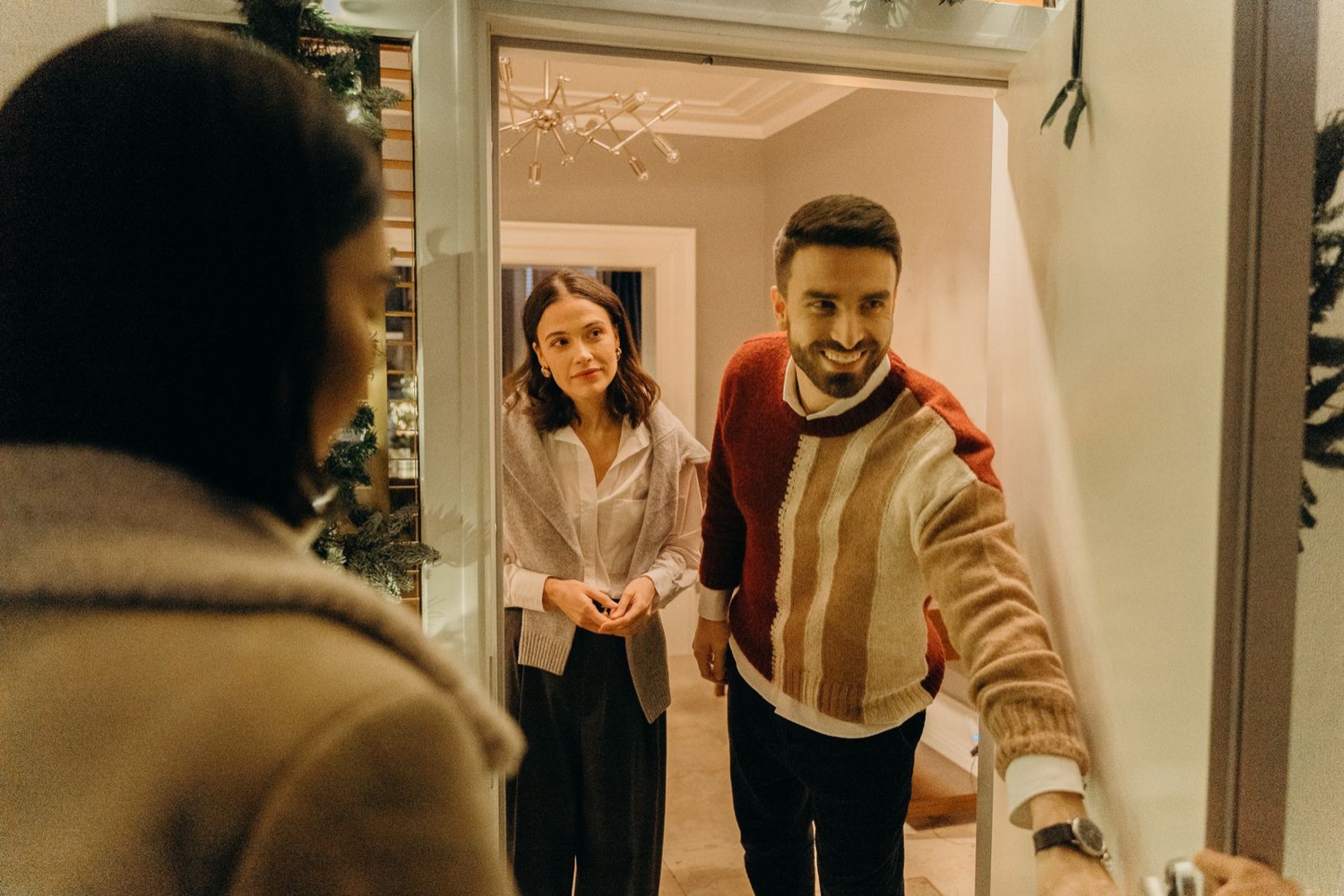 A couple welcoming a guest at their front door
